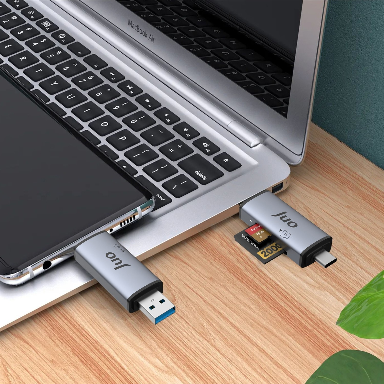 Gümüş USB-C hub dizüstü bilgisayara ve telefona takılı, SD kart takılı.