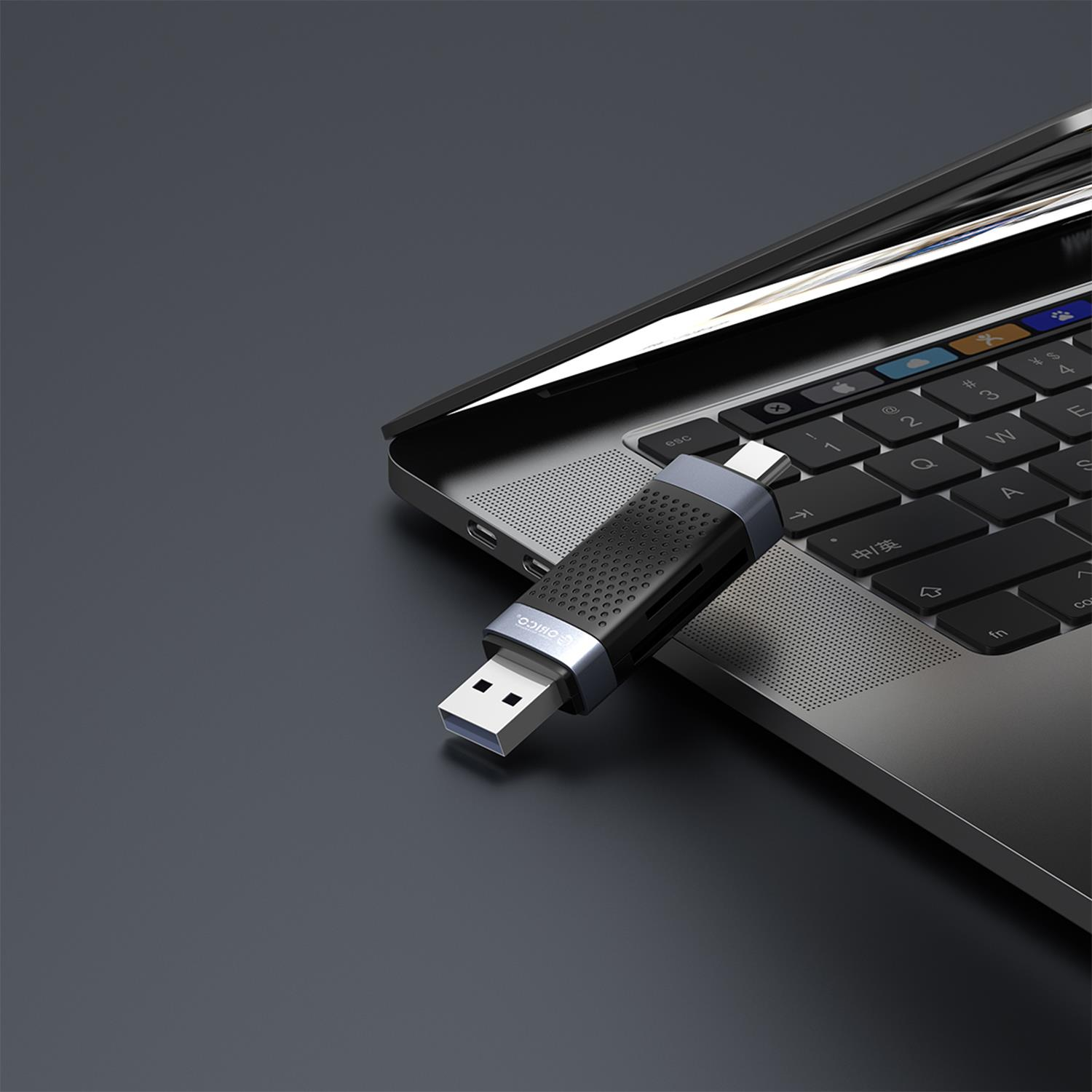 Gümüş vurgulu siyah bir ORICO USB hub, bir dizüstü bilgisayar klavyesine takılıdır.