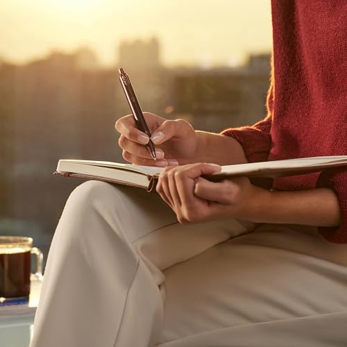Eine Person schreibt mit einem Stift in ein Notizbuch, im Sonnenlicht.