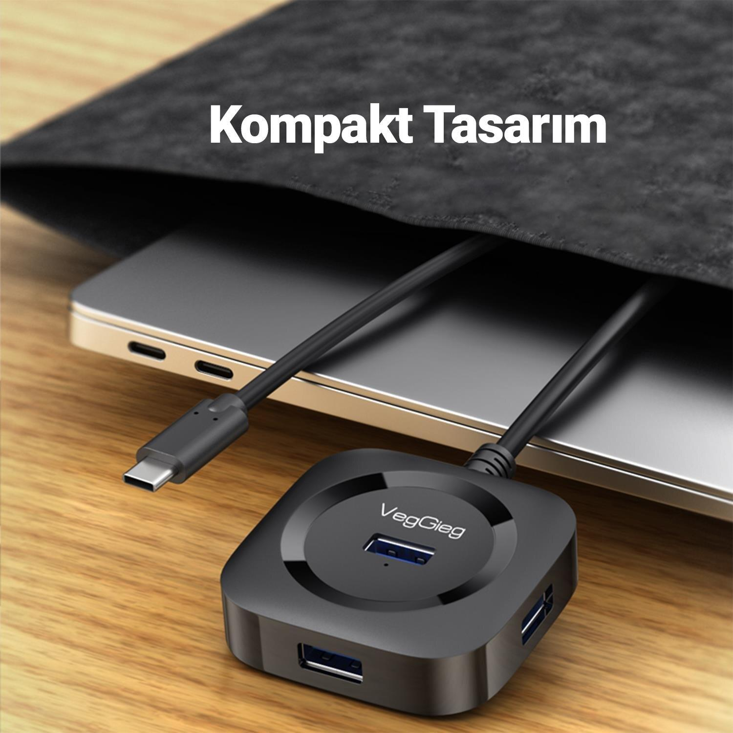 Laptopa bağlı siyah USB hub, gri kılıfın yanında. Metin: Kompakt Tasarim.