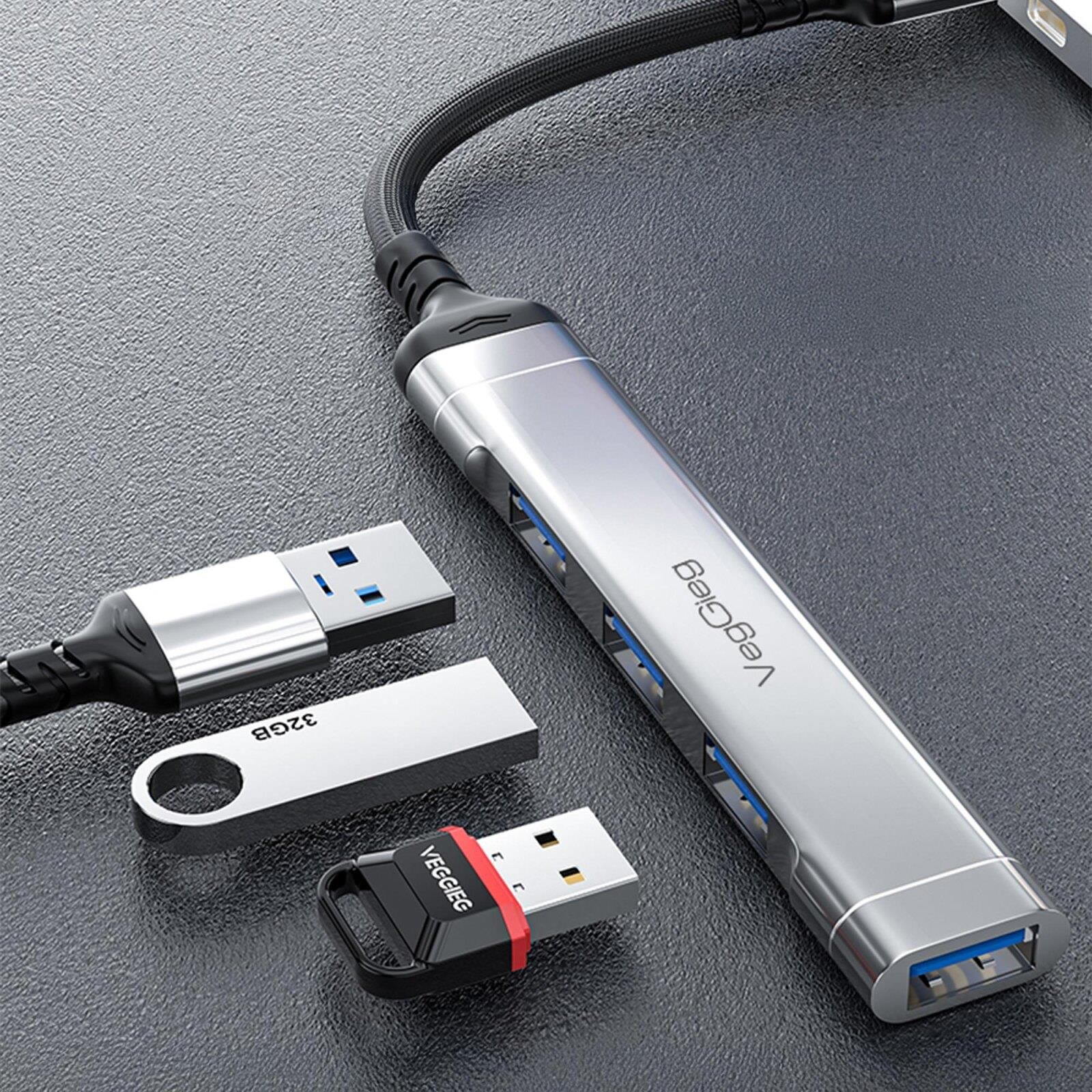 Koyu yüzeyde gümüş renkli, çok portlu USB hub ve üç USB bellek.