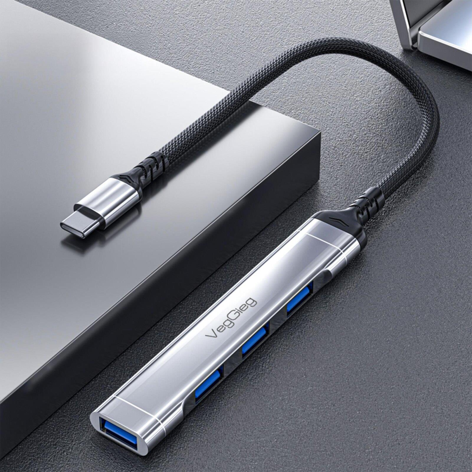 Dört mavi USB bağlantı noktasına sahip gümüş renkli bir USB-C hub masanın üzerinde duruyor.