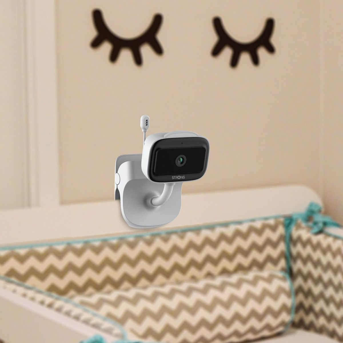 Une caméra de babyphone est fixée à un lit de bébé, avec des autocollants d'yeux au-dessus.