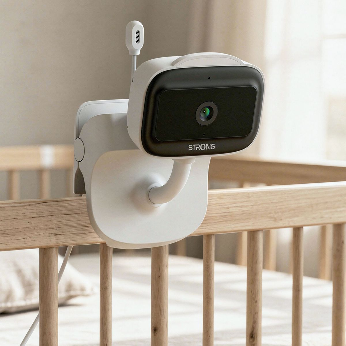 Un babyphone blanc avec caméra est fixé à un lit de bébé en bois.