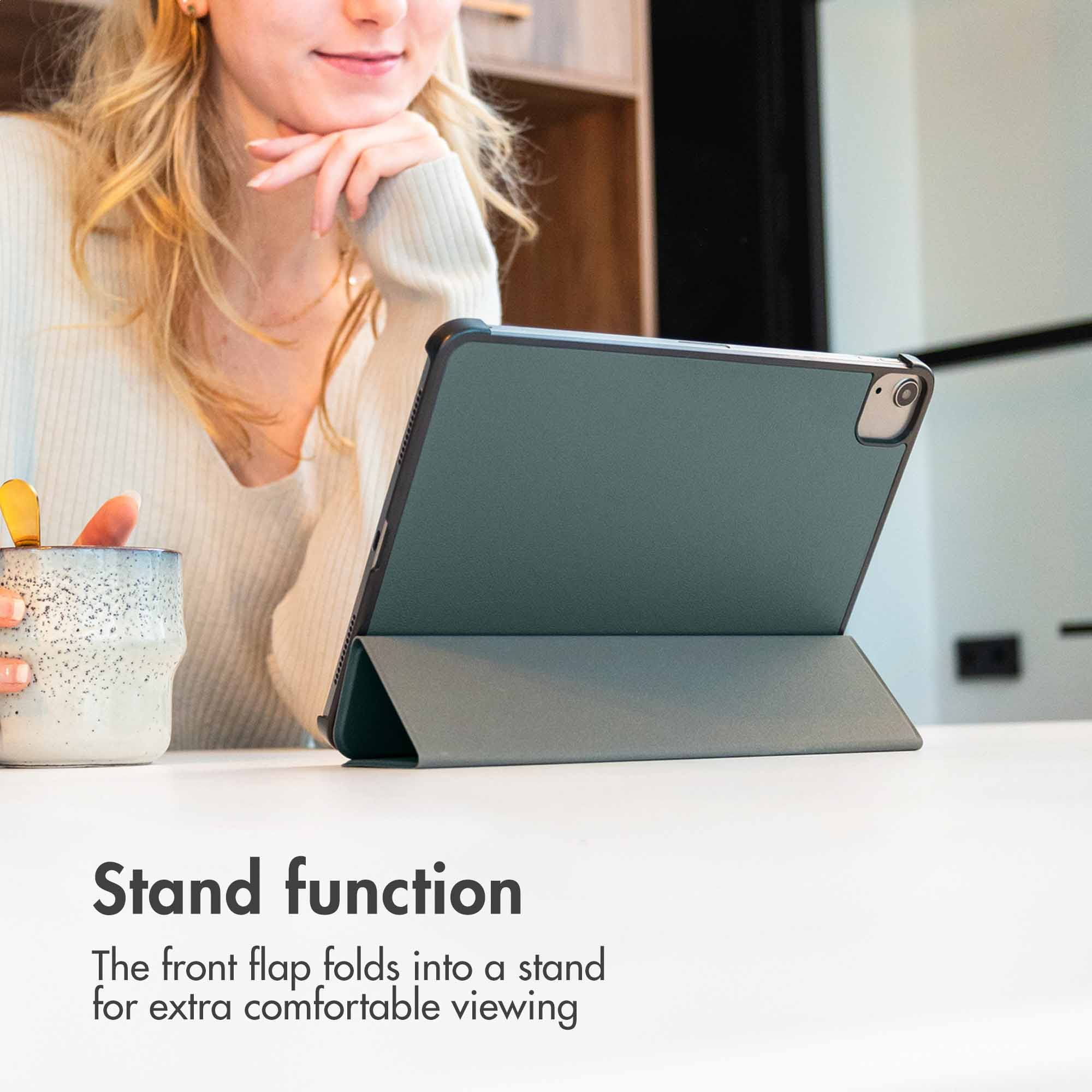 A woman holds a mug, a tablet is propped up. Text: Stand function.