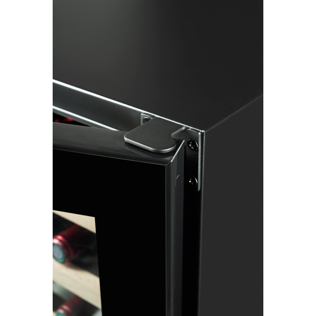 Primer plano de una puerta de refrigerador negra con bisagra metálica y botellas de vino visibles.