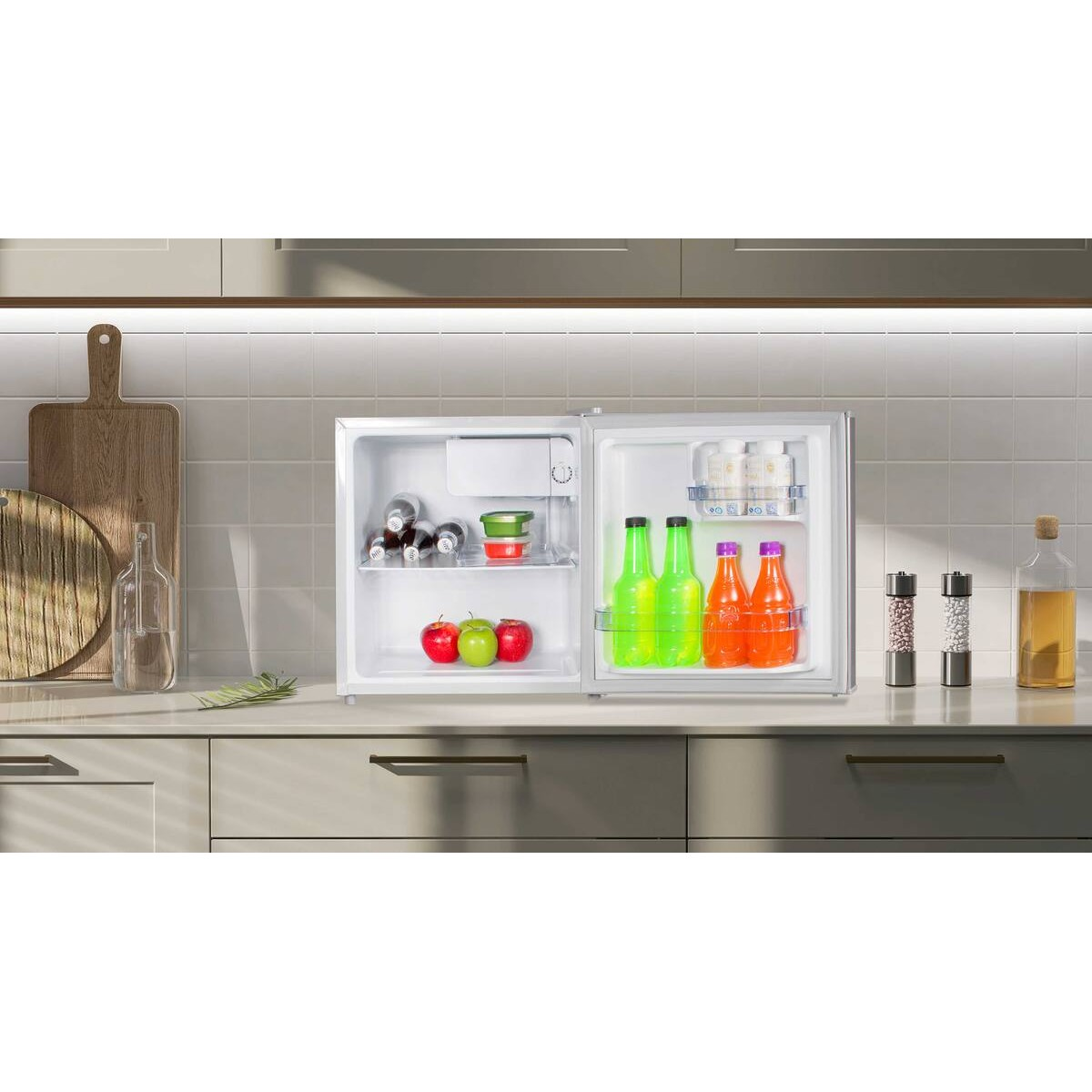 Una pequeña nevera abierta con bebidas, manzanas y botellas en estantes. Encimera de cocina.
