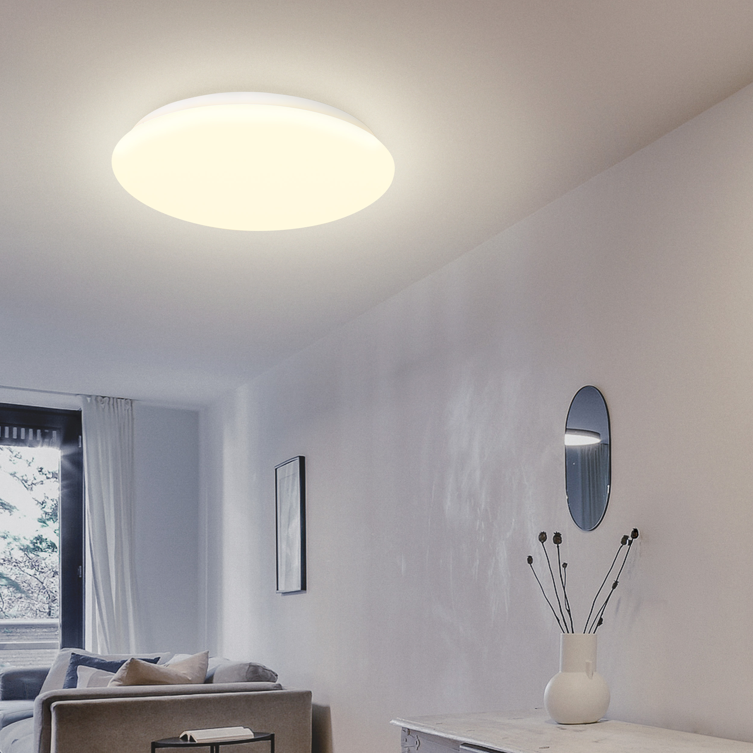 Ein heller runder Deckenventilator beleuchtet ein modernes Wohnzimmer mit Sofa und Spiegel.
