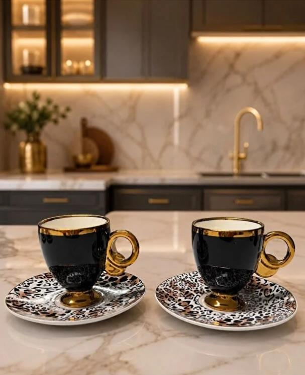 Leopar desenli fincan altlıkları üzerinde altın süslemeli ve kulplu iki siyah espresso fincanı.