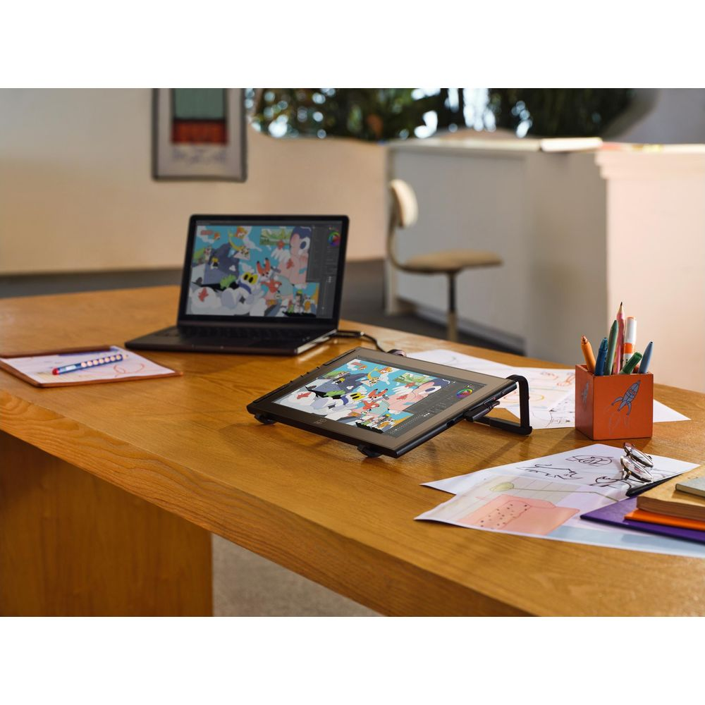 Ein Laptop und ein Grafiktablett mit bunter Kunst auf einem Holztisch.