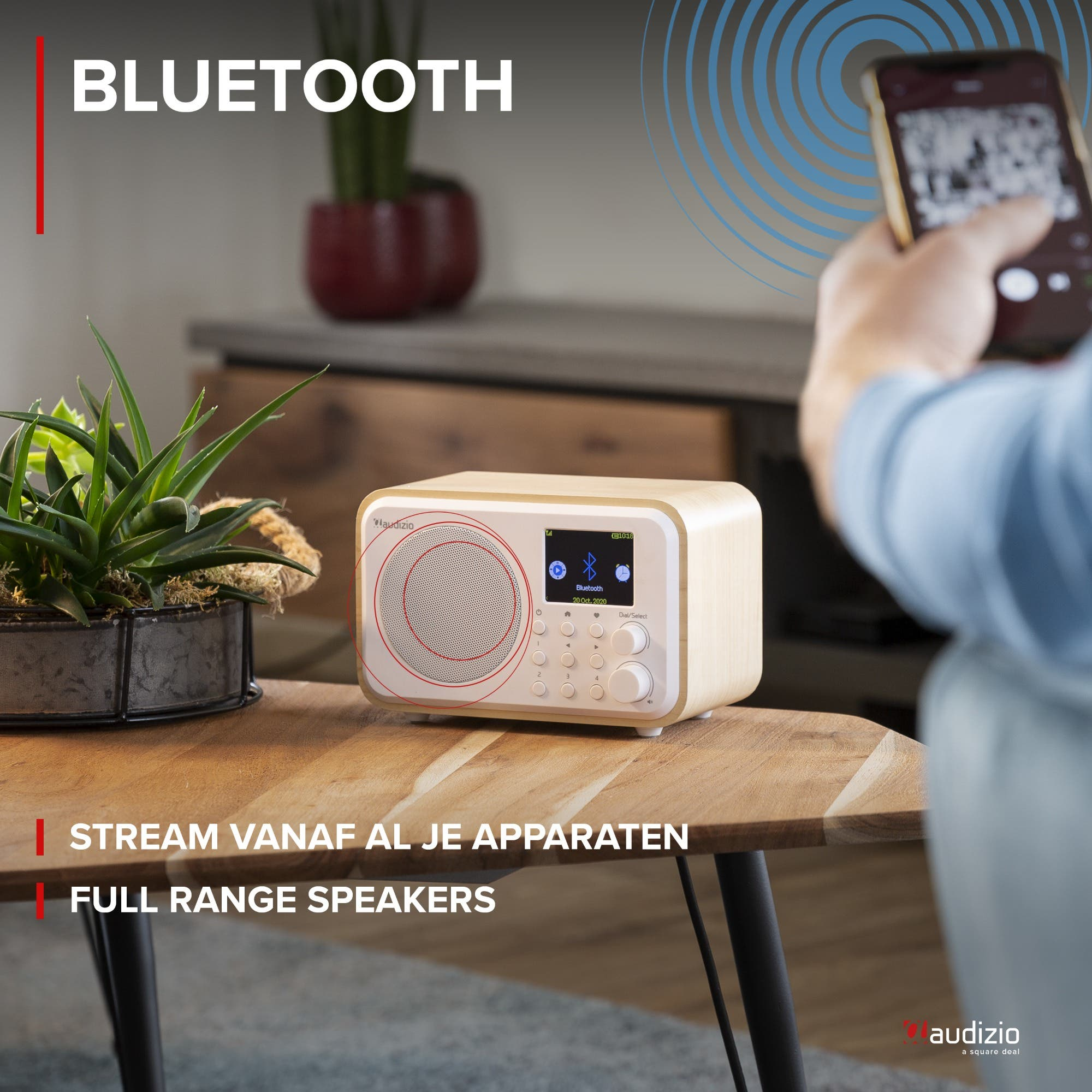 Un hombre sostiene un teléfono inteligente frente a una radio de madera. "BLUETOOTH" está arriba.