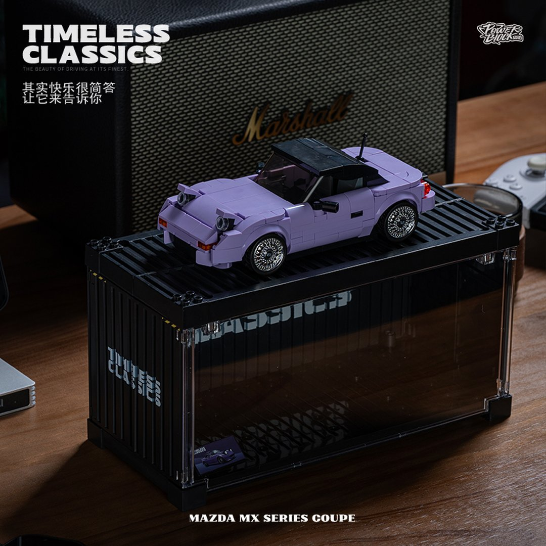 Fioletowy model Lego Mazda MX Series Coupe jest wystawiony na czarnym kontenerze.