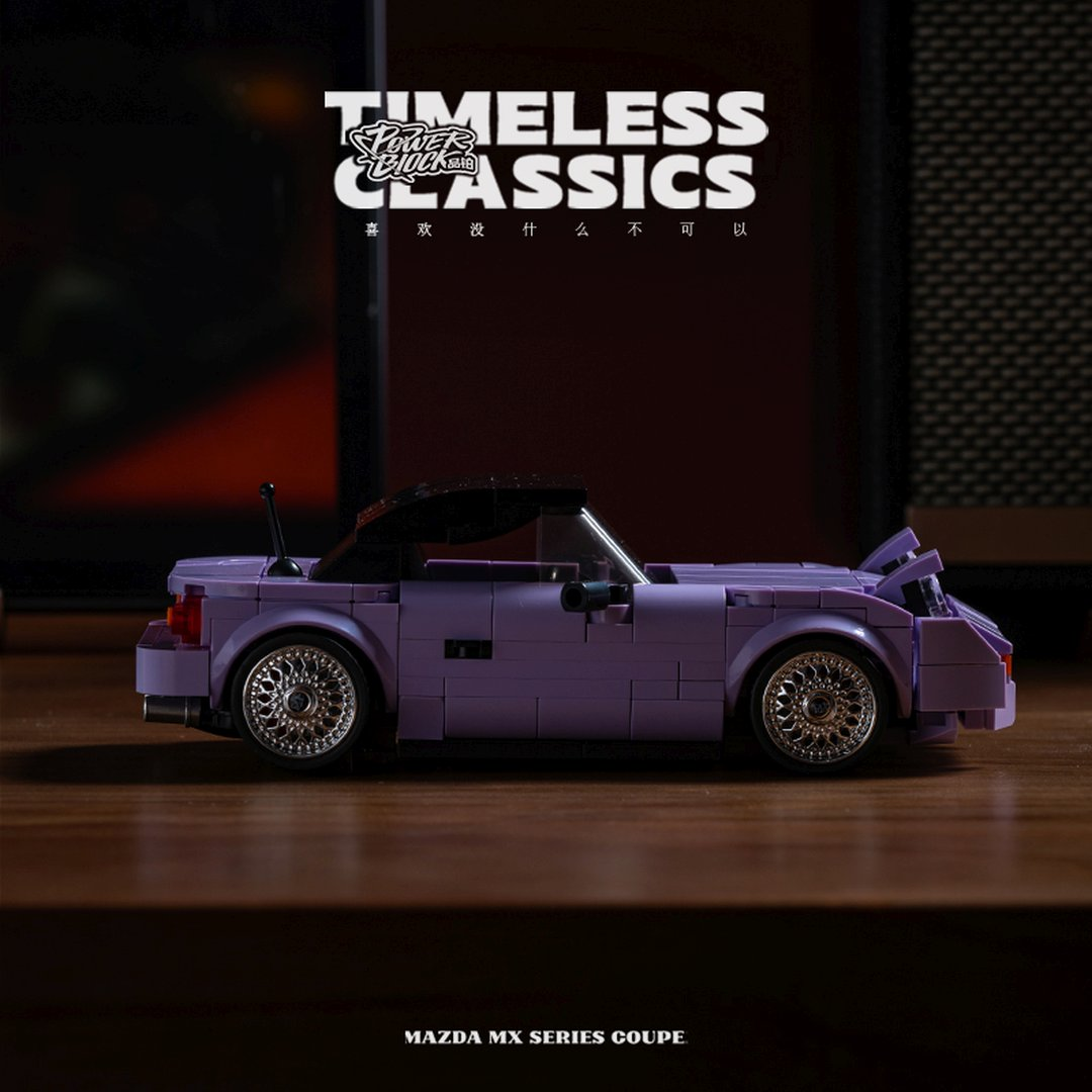Fioletowy samochód Lego, Mazda MX Series Coupe, stoi na drewnianym stole.