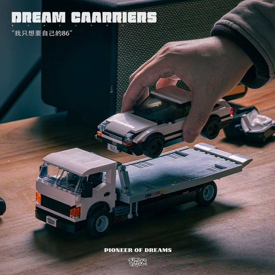Dłoń umieszcza biały samochód Lego na lawecie Lego. Tekst: 'DREAM CARRIERS'.