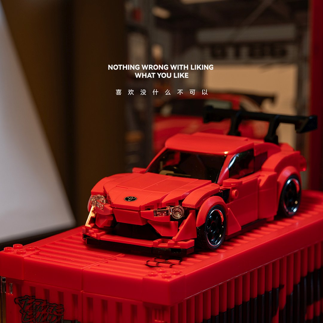 Czerwony model samochodu sportowego Lego ze spojlerem stoi na czerwonej podstawie.
