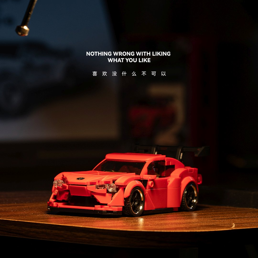 Czerwony model samochodu sportowego Lego ze spojlerem na drewnianym stole.