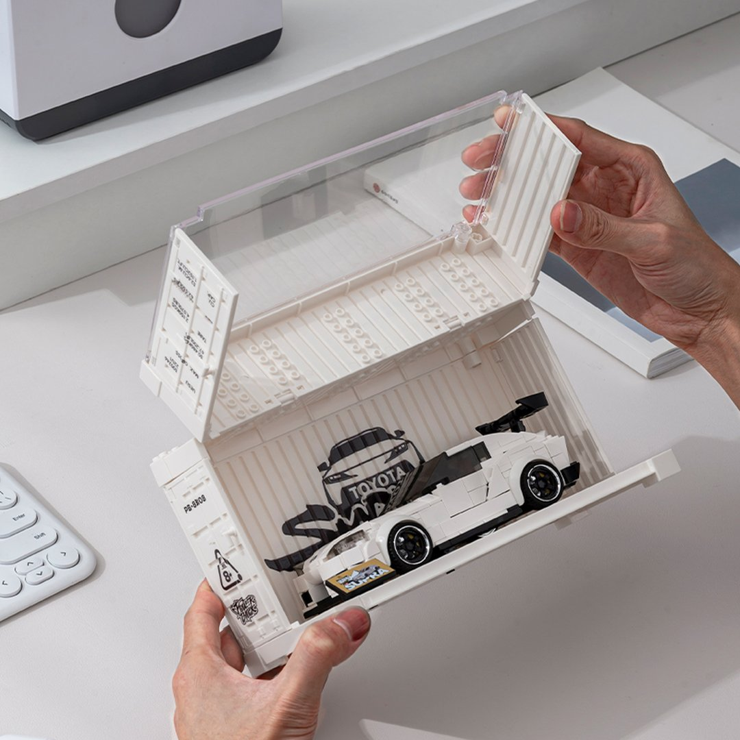 Biały samochód Lego w pojemniku trzymanym przez ręce.