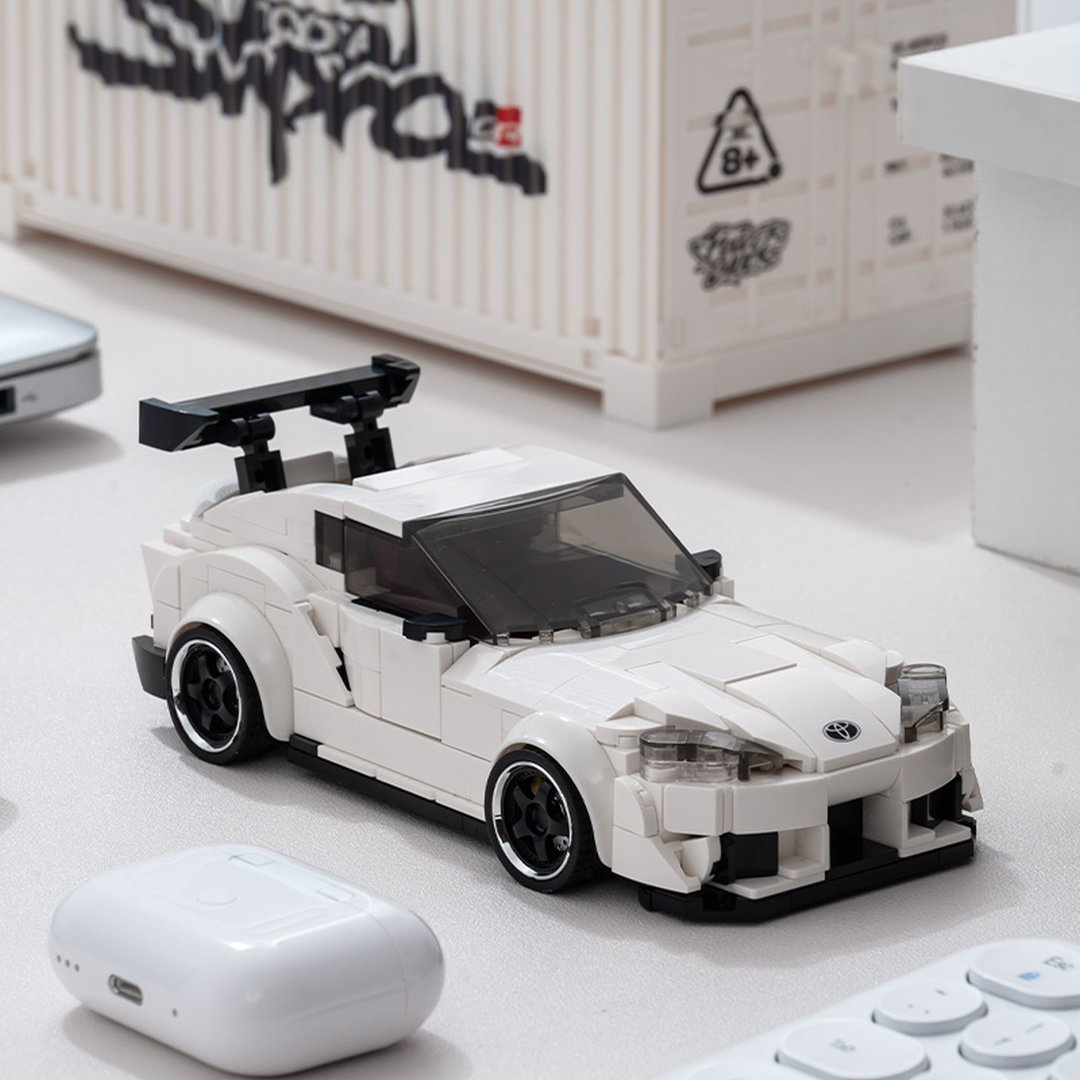 Biały model samochodu sportowego Lego z czarnym spojlerem na stole.
