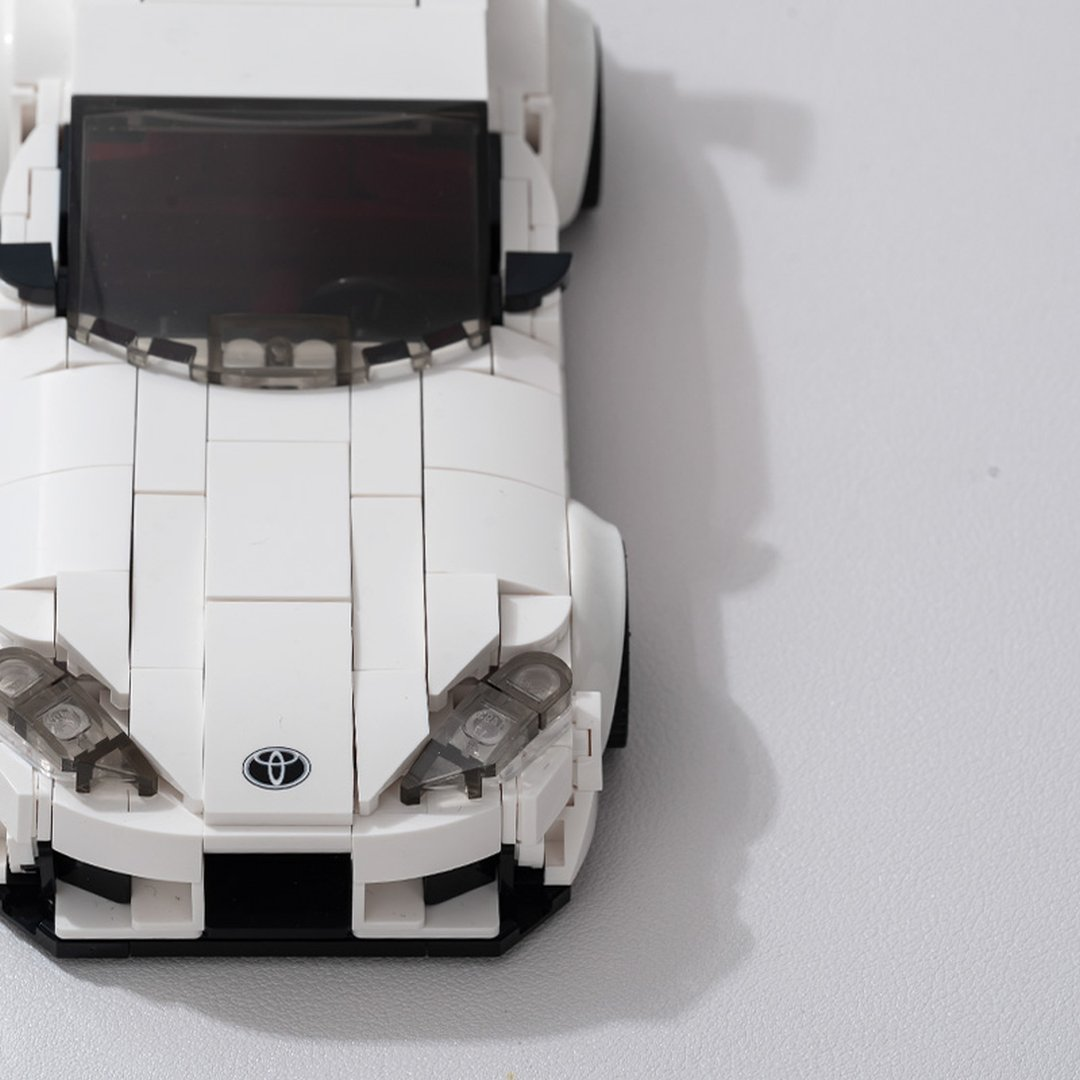 Biały model samochodu sportowego Lego z przezroczystymi światłami i logo Toyota.