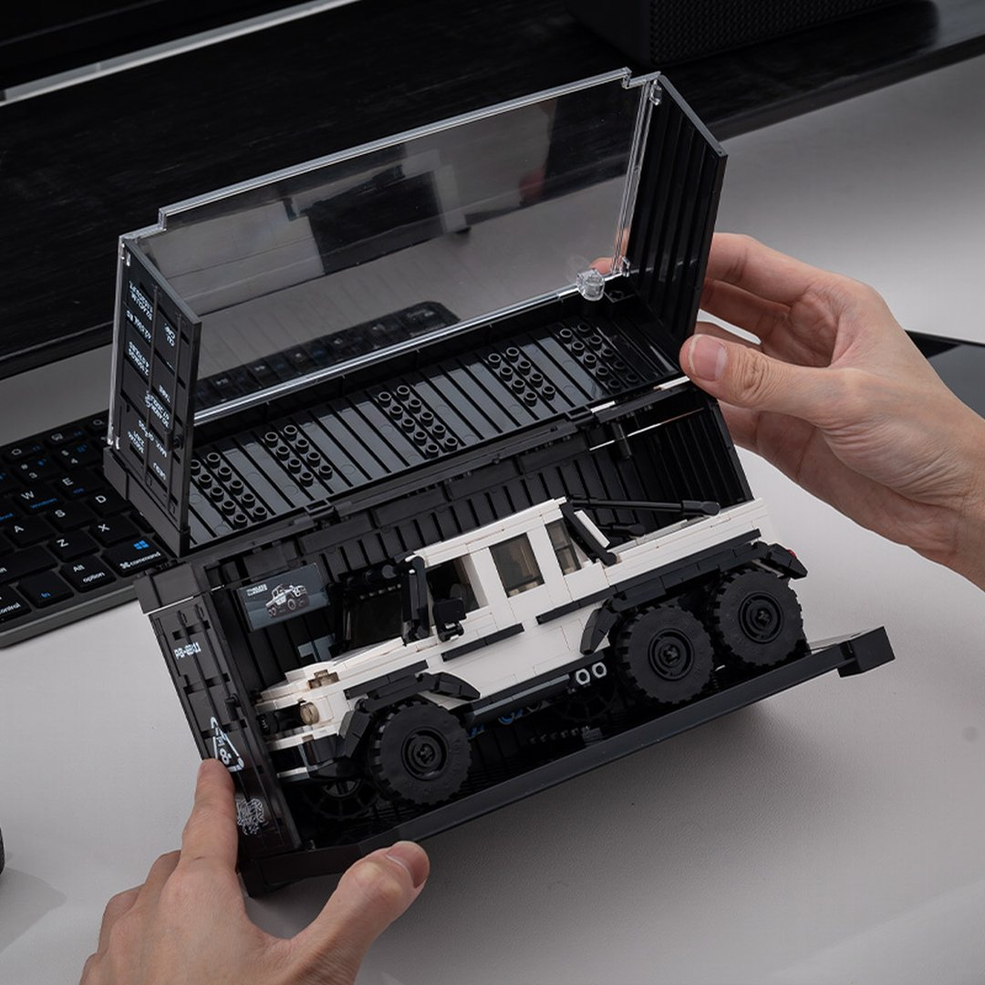 Biała, sześciokołowa ciężarówka Lego w czarnym pojemniku.