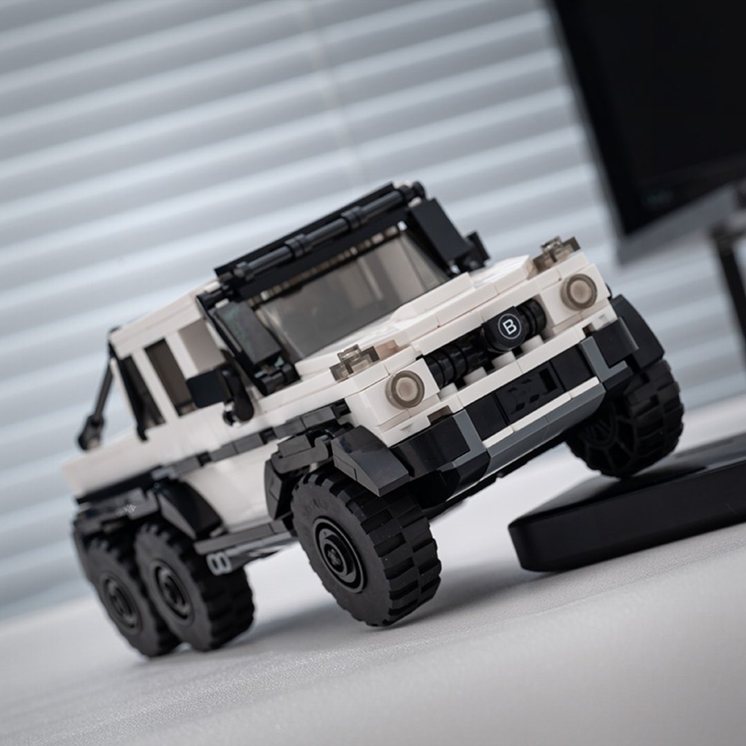 Biało-czarny SUV Lego z 6 kołami i bagażnikiem dachowym, widok pod kątem.