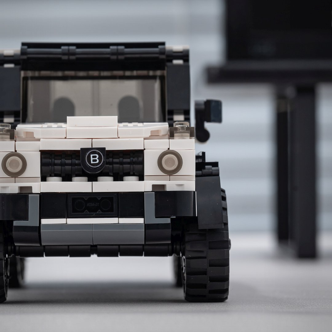 Widok z przodu białego i czarnego SUV-a Lego z logo B na grillu.
