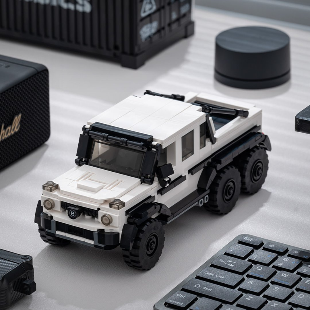 Białe sześciokołowe Lego SUV stoi obok głośnika Marshall i klawiatury.