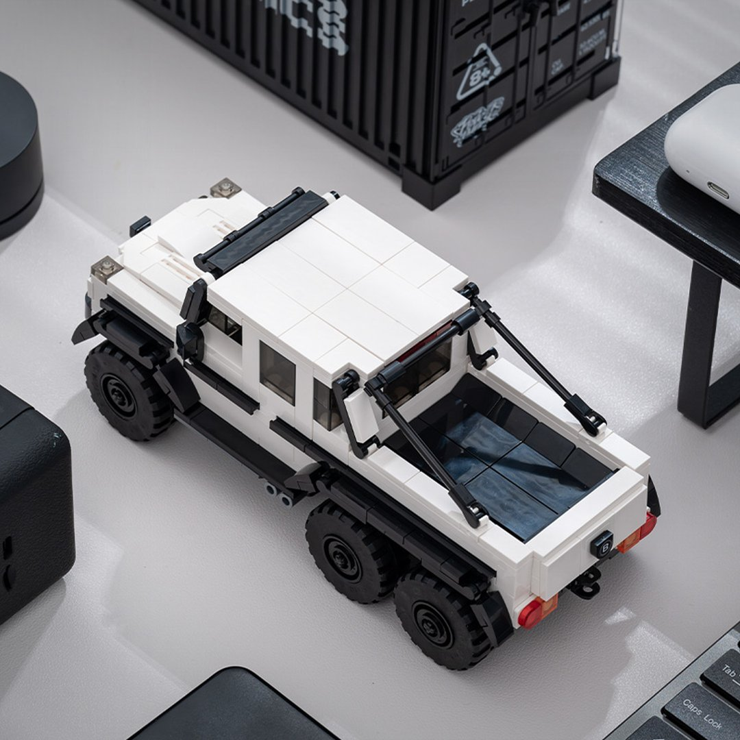 Biały sześciokołowy pojazd Lego, szczegółowy, na szarym tle.