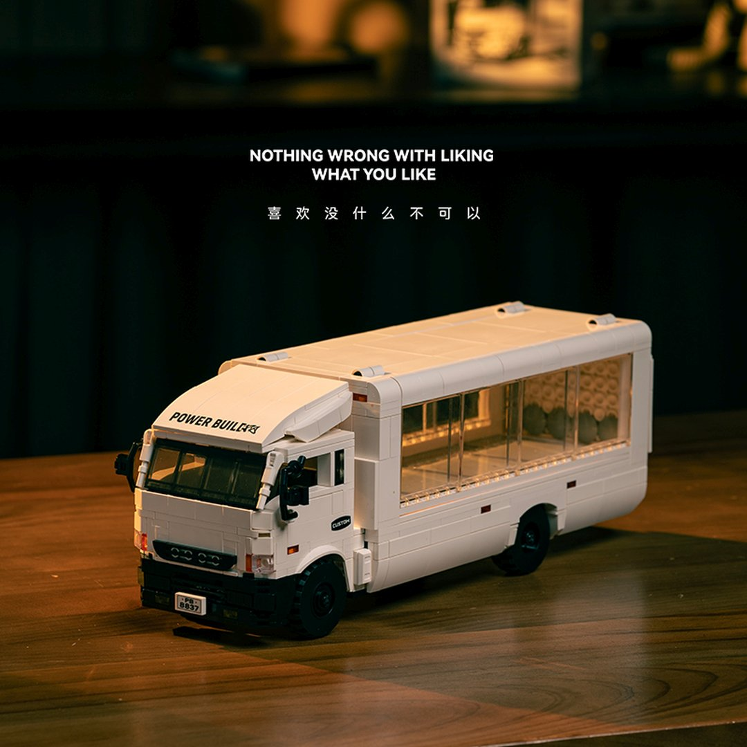 Biały autobus Lego na drewnianym stole. Napis: Nic złego w lubieniu tego, co lubisz.