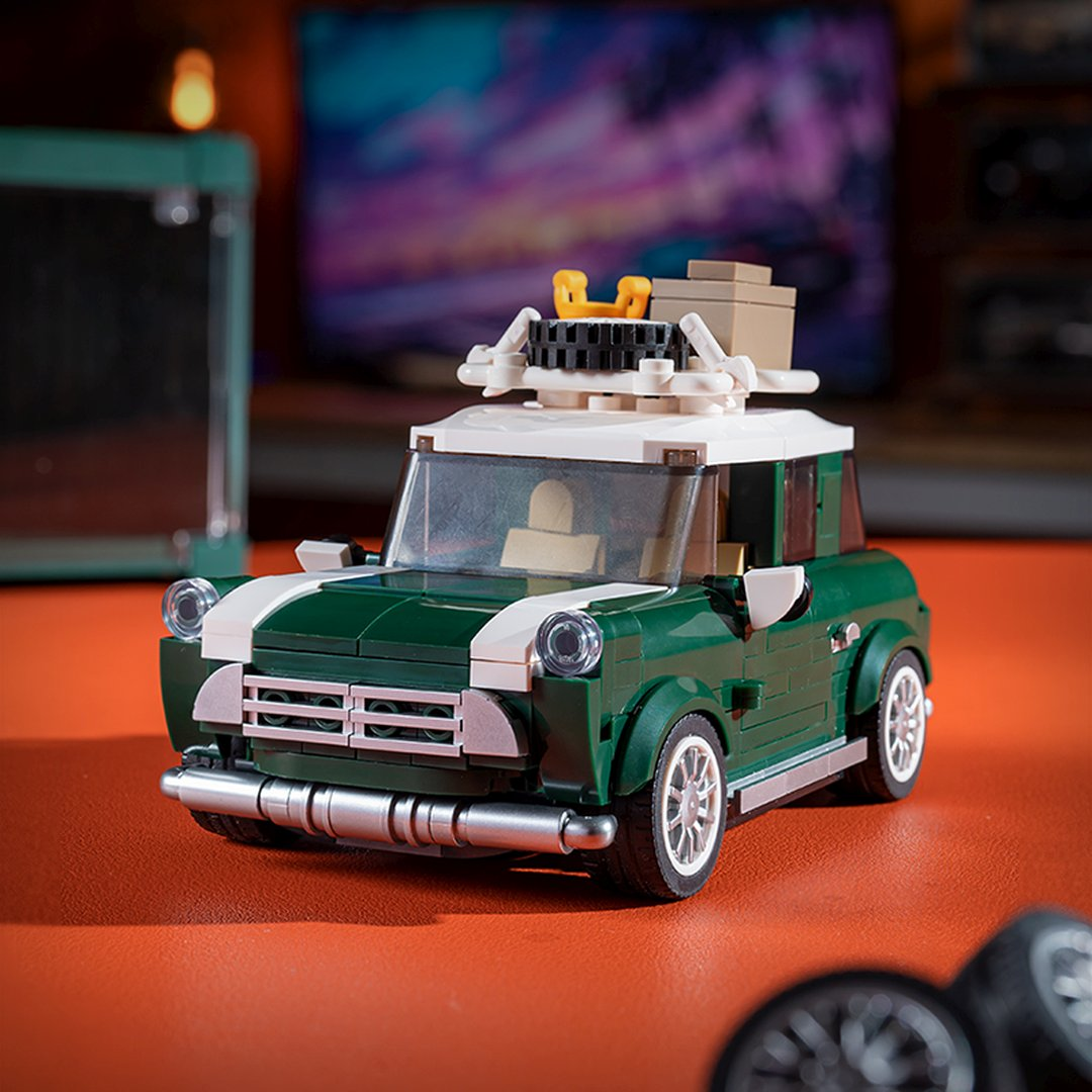 Zielony model Lego Mini Cooper z białym dachem na pomarańczowej powierzchni.