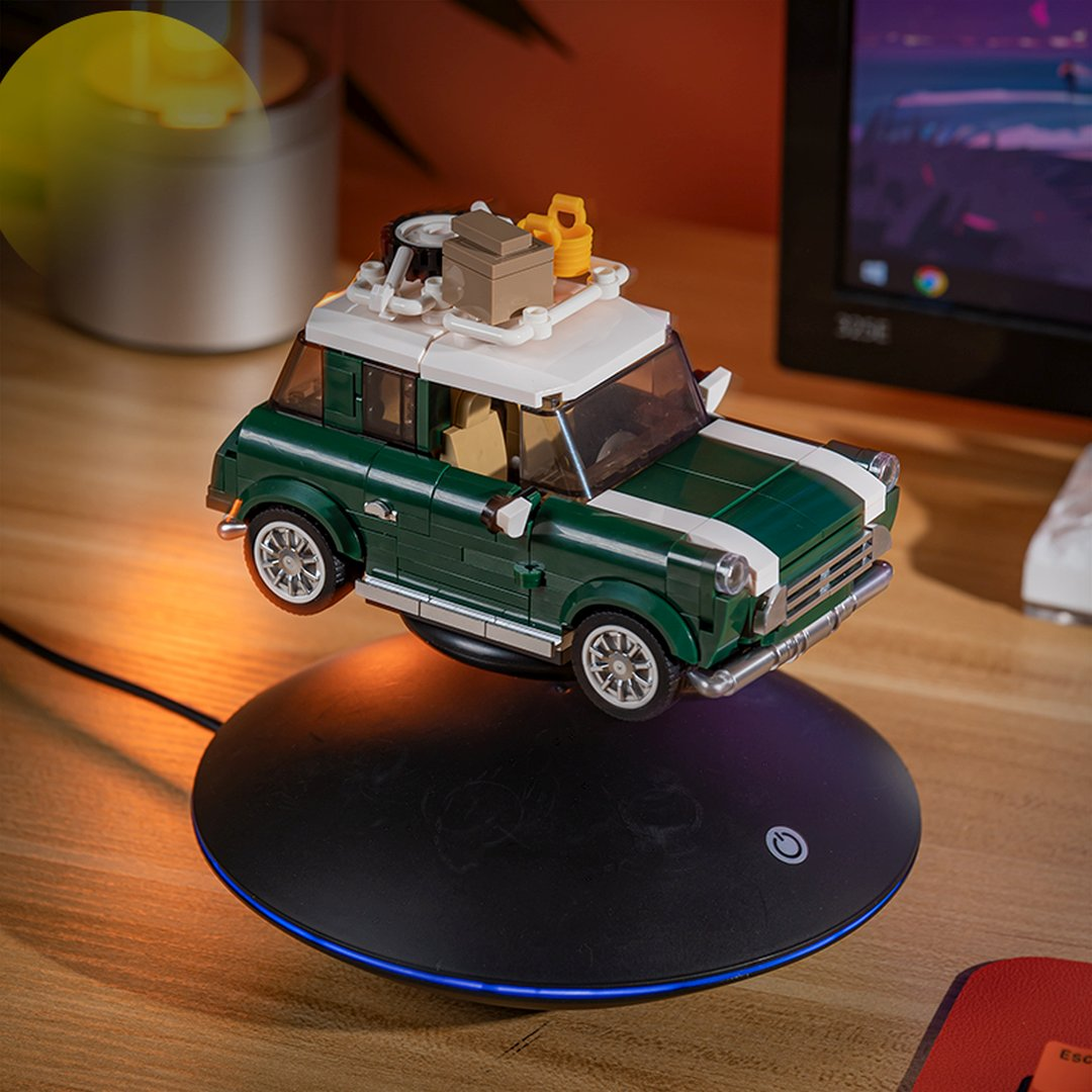 Zielone Lego Mini Cooper lewituje na czarnej ładowarce z niebieskim światłem.