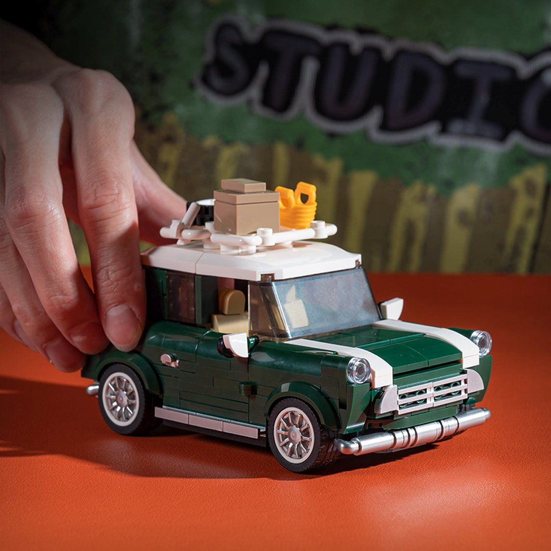 Zielony Mini Lego z białym dachem i bagażnikiem dachowym, trzymany przez rękę.