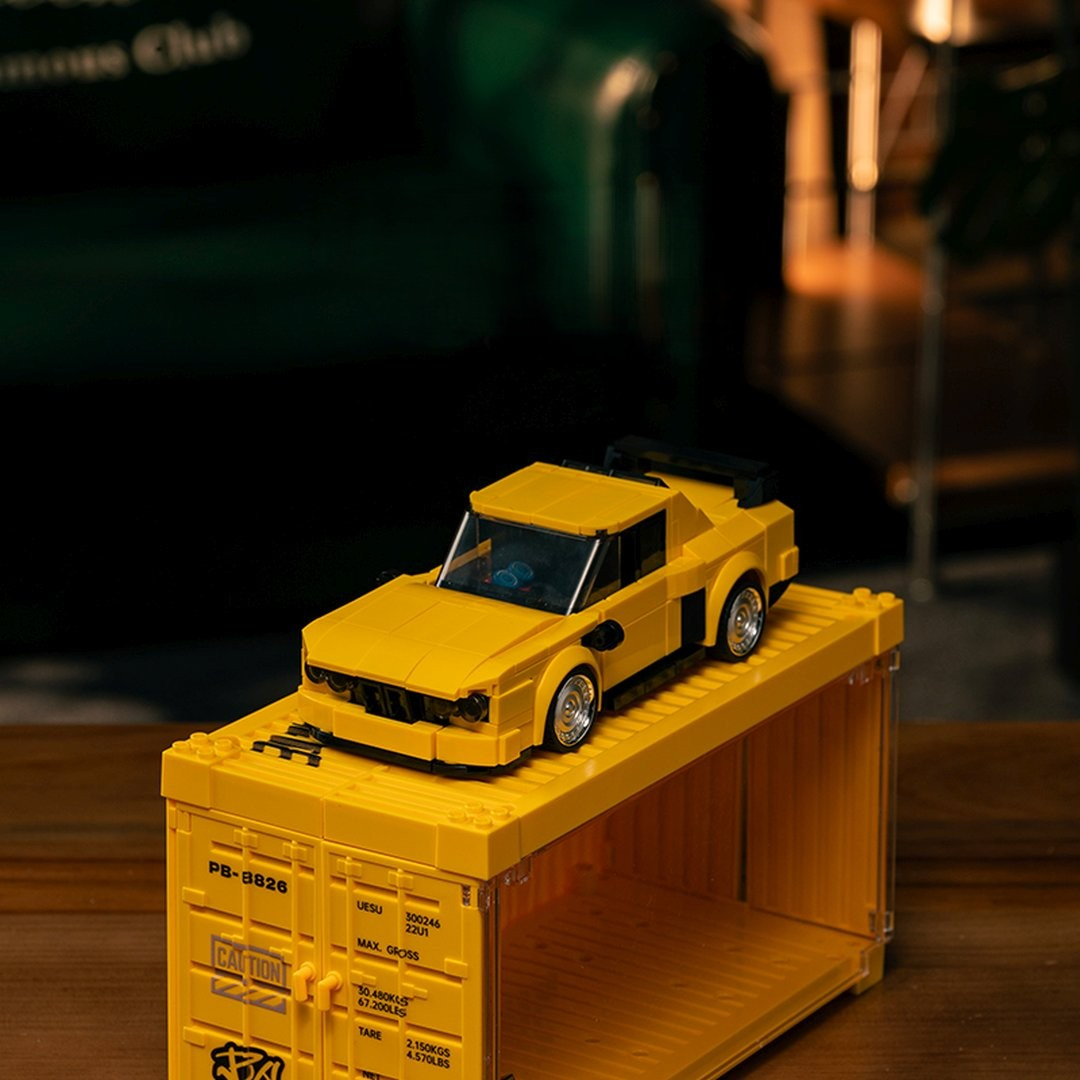 Żółty samochód Lego stoi na żółtym kontenerze Lego.