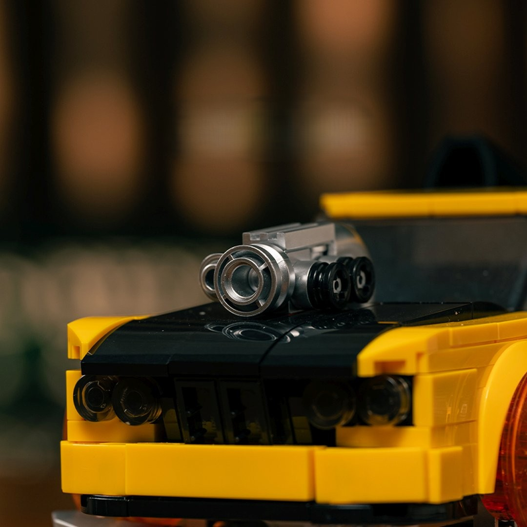 Żółty samochód sportowy Lego z czarną maską i srebrnym silnikiem na górze.
