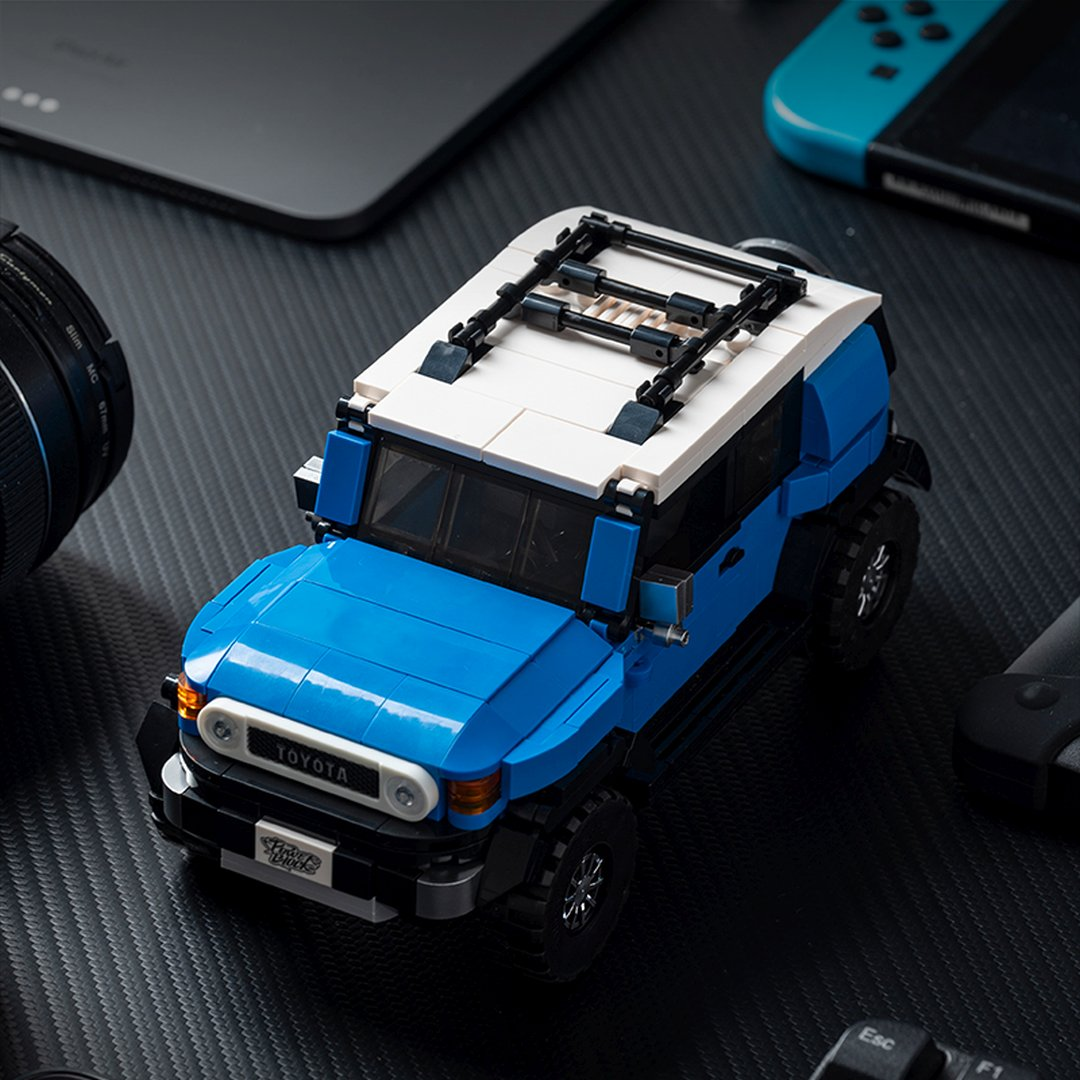 Niebiesko-biały LEGO Toyota FJ Cruiser z bagażnikiem dachowym na czarnej powierzchni.