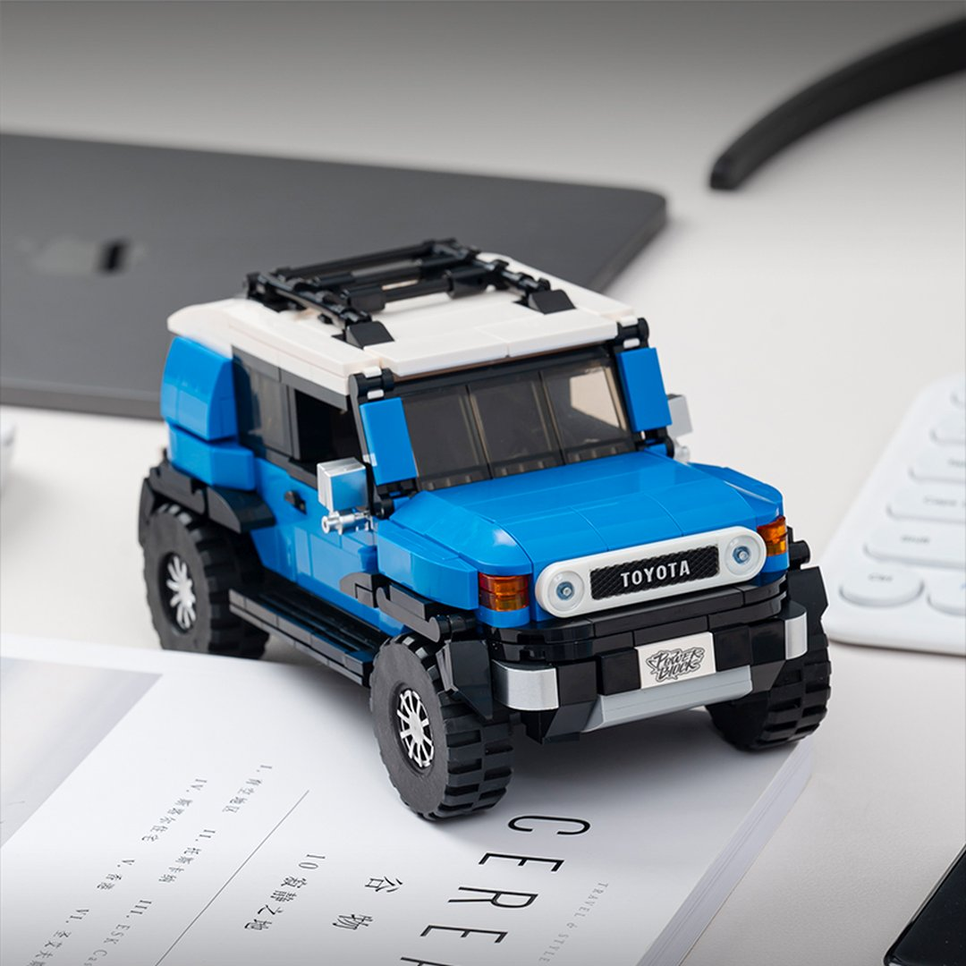Niebiesko-biały samochód Toyota FJ Cruiser z klocków na książce.