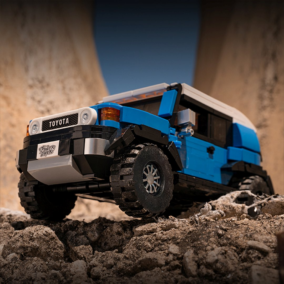 Niebieski i biały SUV Lego na skalistym terenie.
