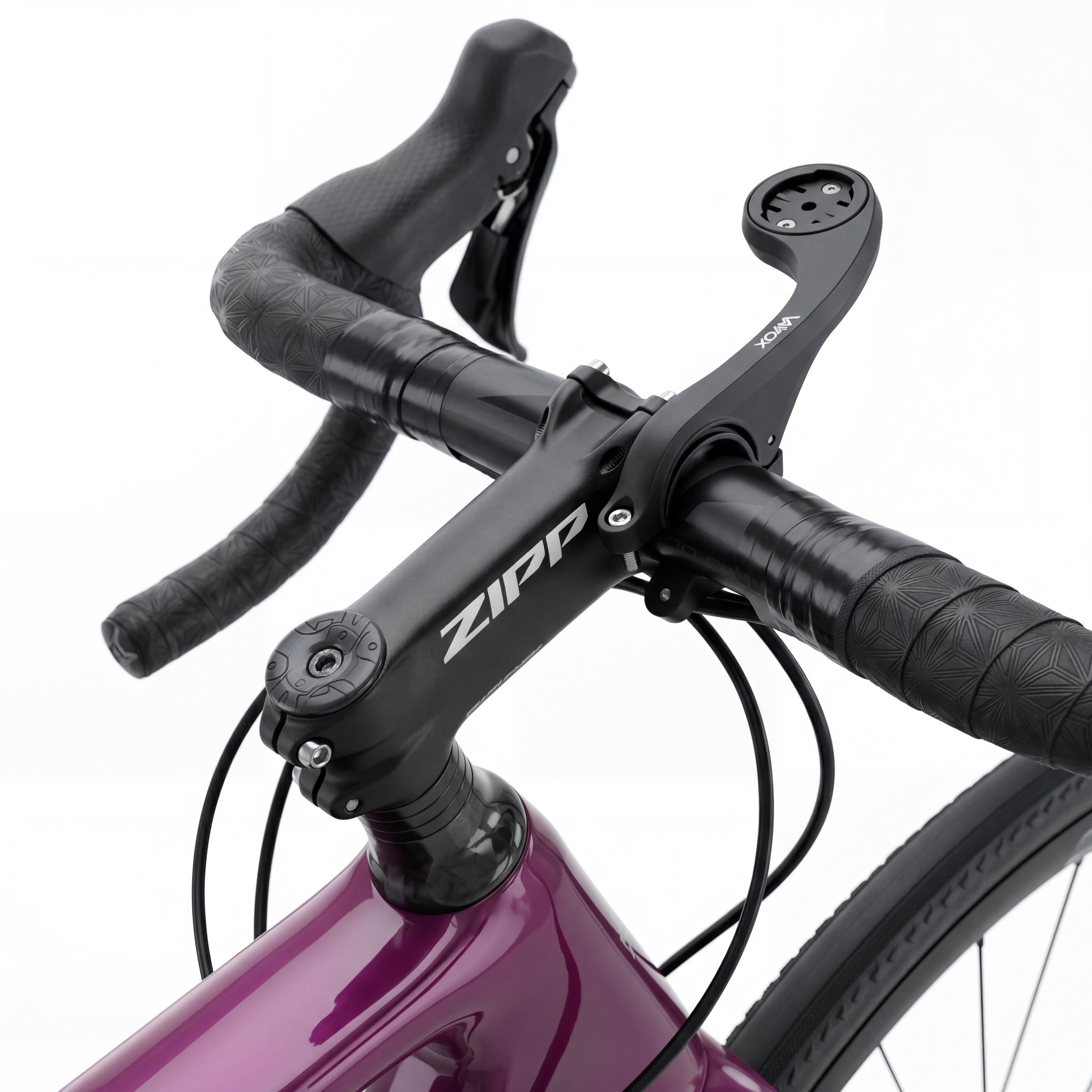 Zbliżenie kierownicy fioletowego roweru ze wspornikiem ZIPP i uchwytem na komputer.