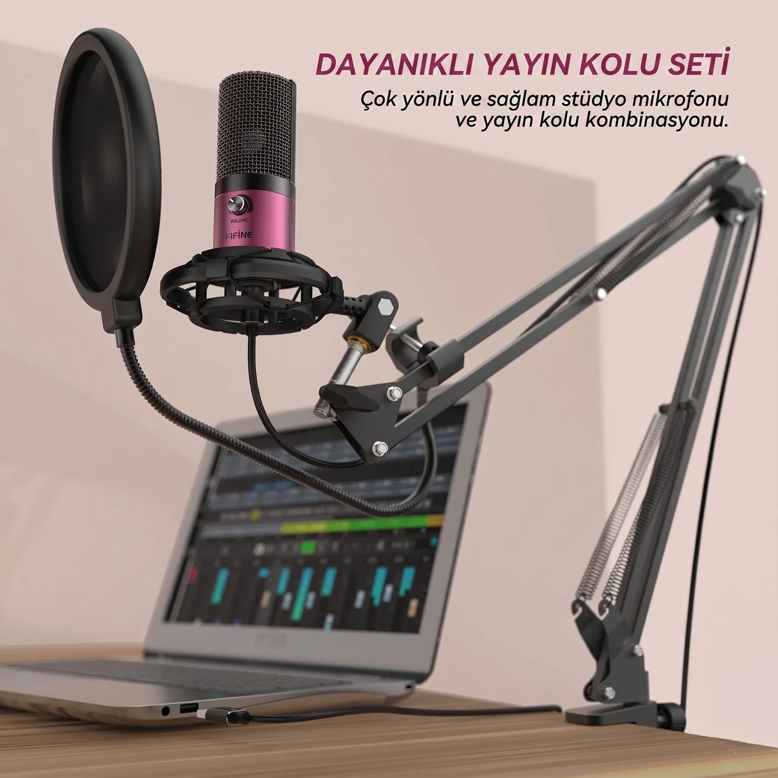 Pop filtreli ve mikrofon kollu pembe mikrofon, dizüstü bilgisayarın yanında.