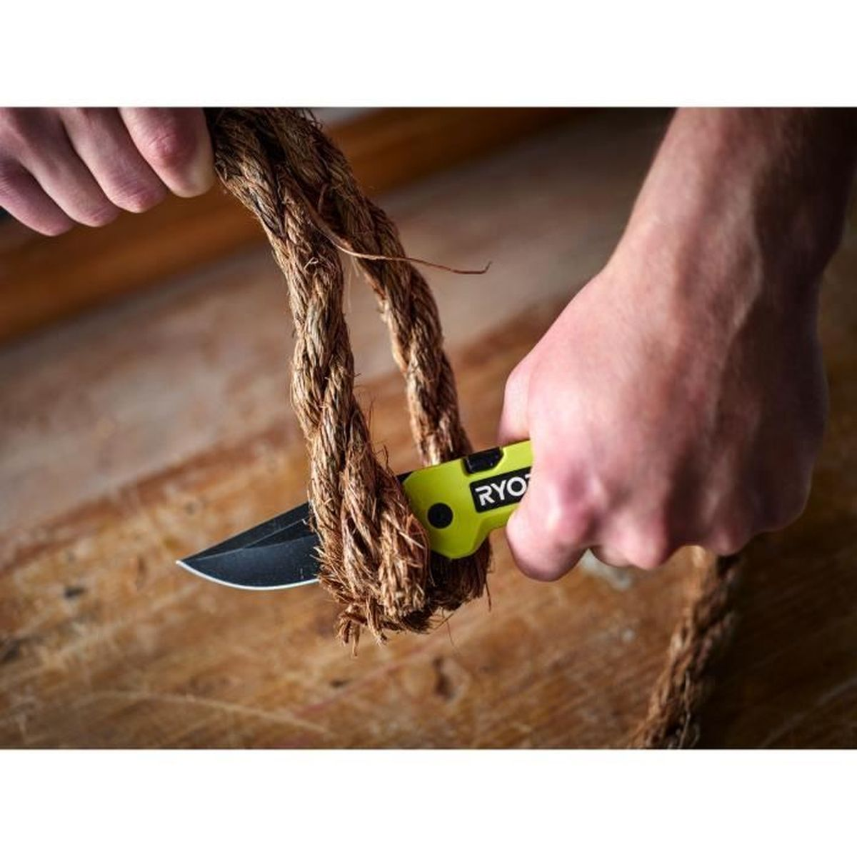 Una persona corta una cuerda gruesa con un cuchillo amarillo sobre una mesa de madera.