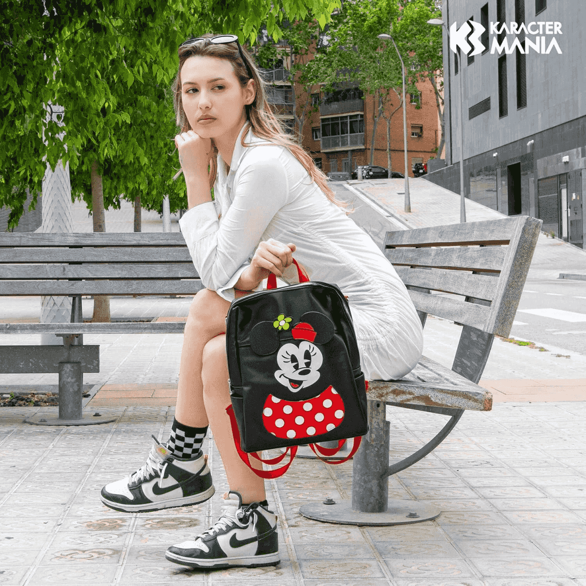 Eine Frau sitzt auf einer Bank mit einem Minnie Maus Rucksack.