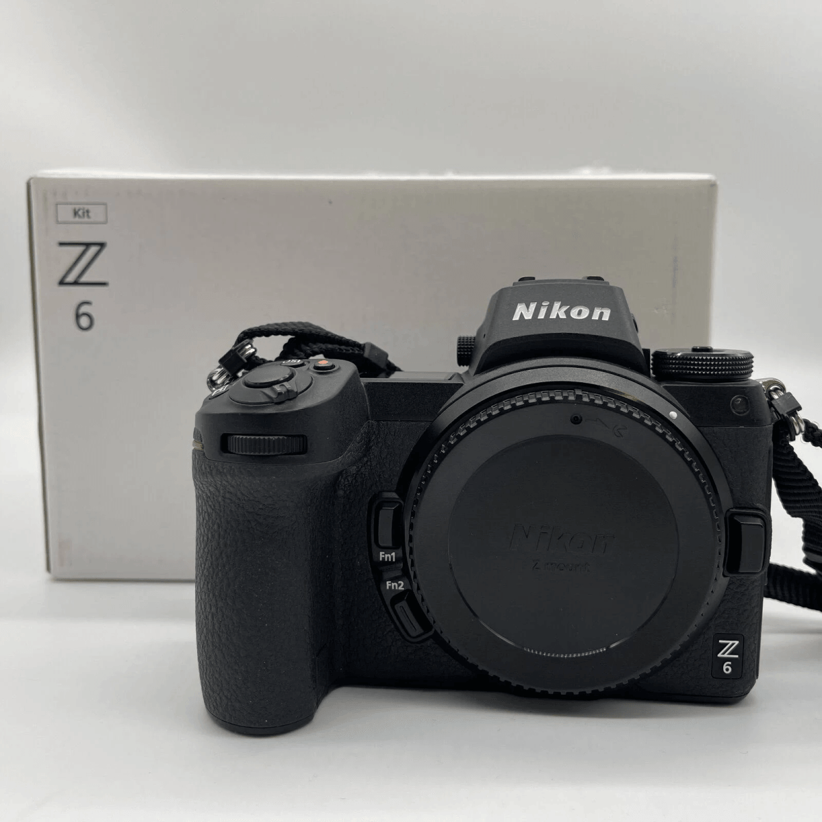 Cámara Nikon Z6 negra con tapa de lente y caja al fondo.