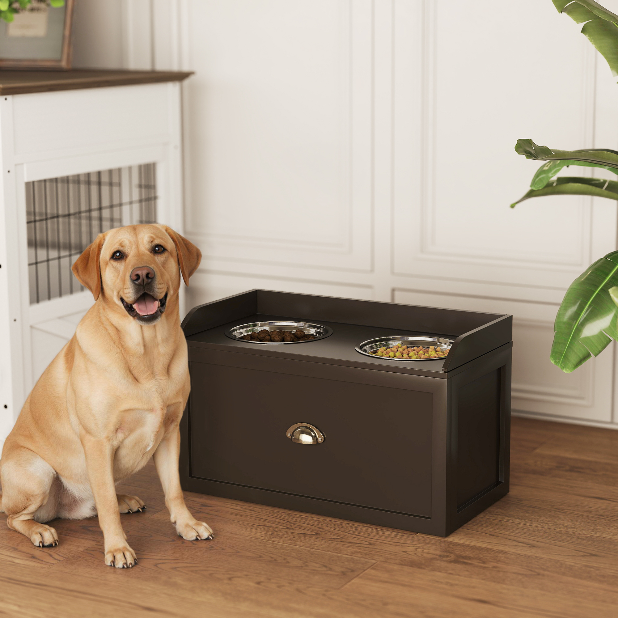 Un Labrador color miele seduto su un pavimento in legno accanto a una credenza scura con due ciotole.