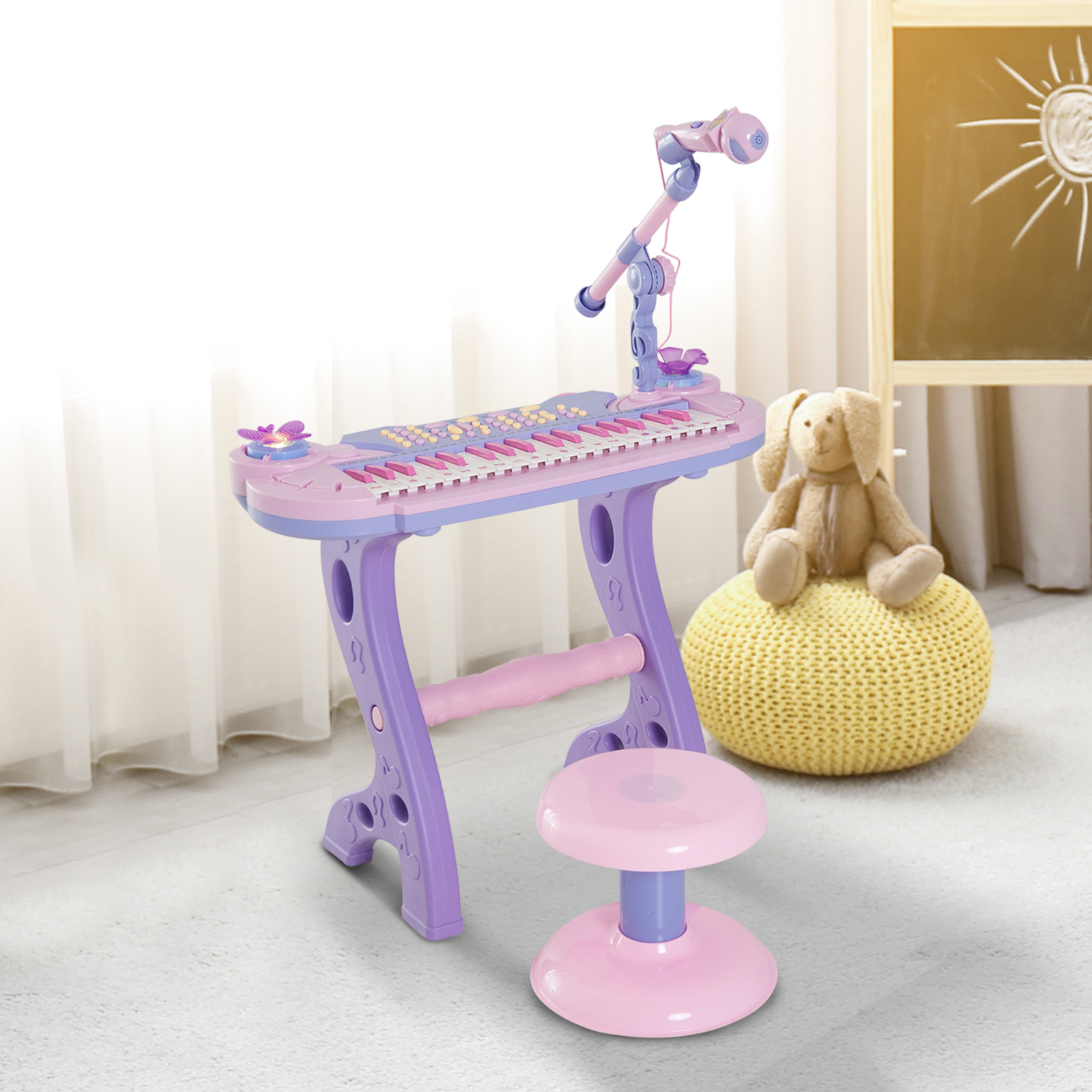 Tastiera giocattolo viola con microfono, sgabello e orsacchiotto su pouf.