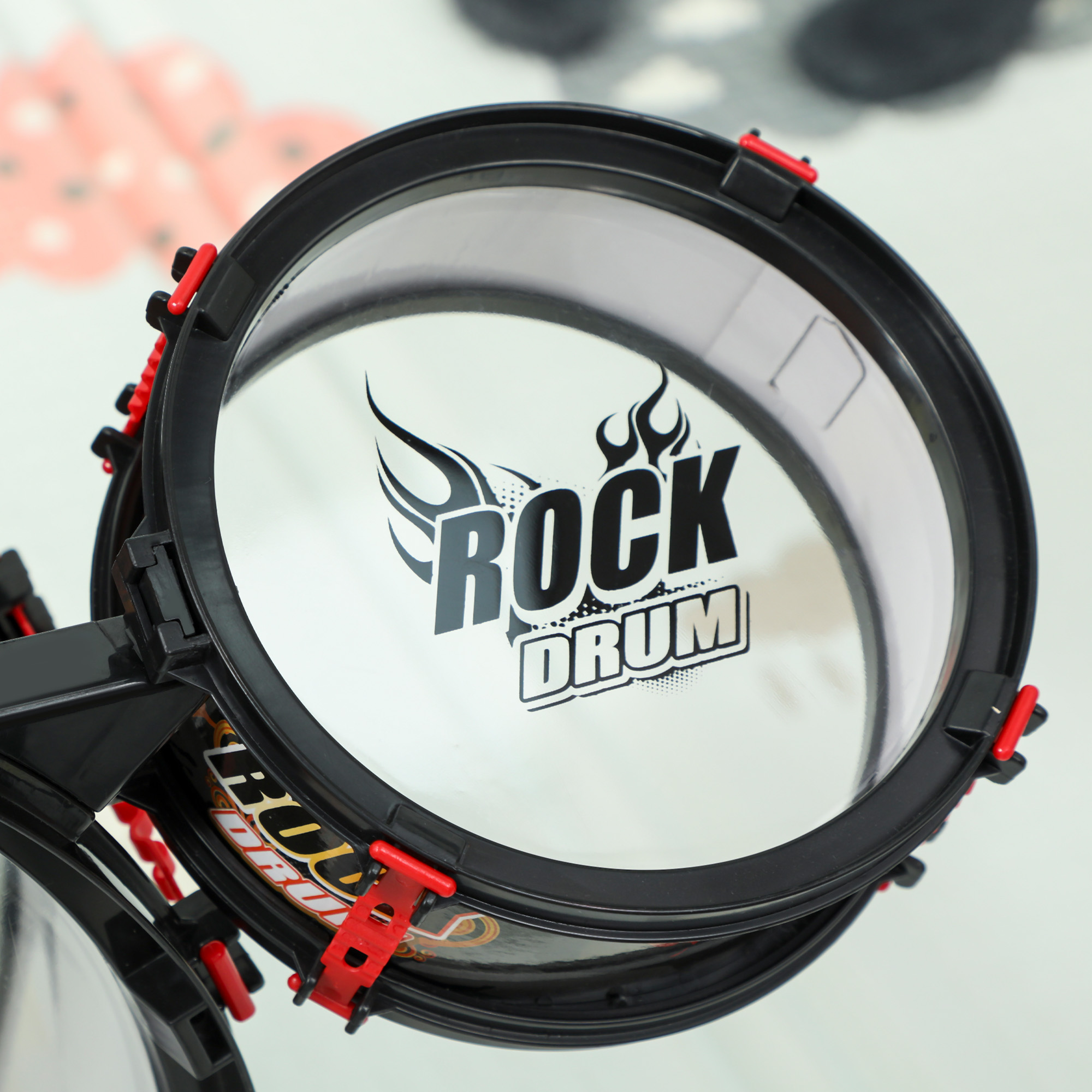 Un giocattolo batteria rock nero con accenti rossi e logo a fiamma.