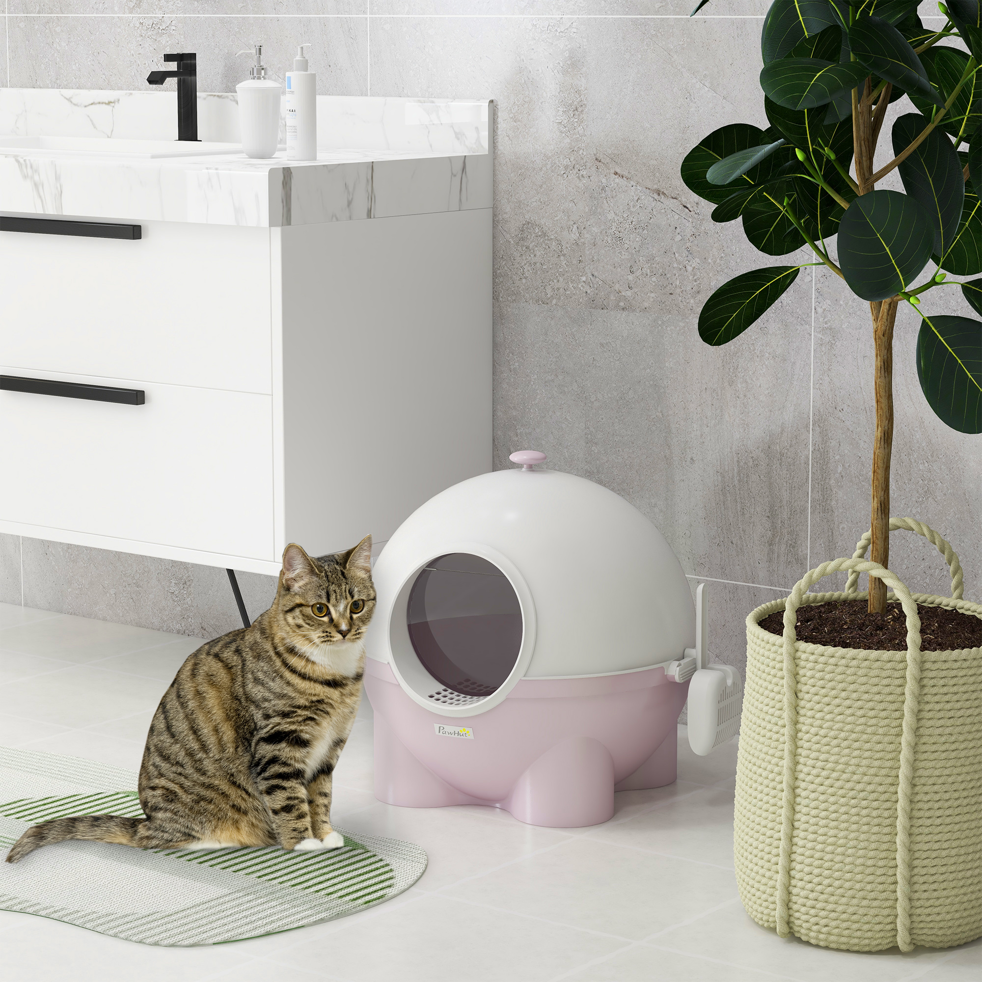 Un gatto soriano seduto su un tappeto vicino a una lettiera rosa e bianca.