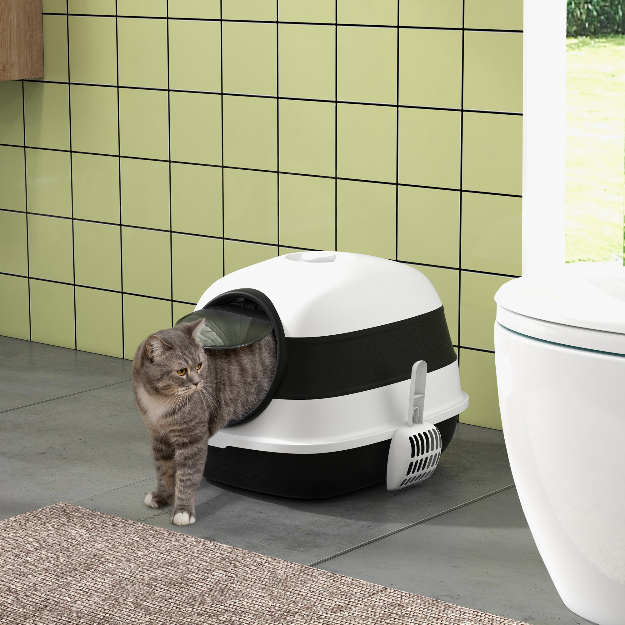 Un gatto soriano si trova accanto a una lettiera chiusa e un water.