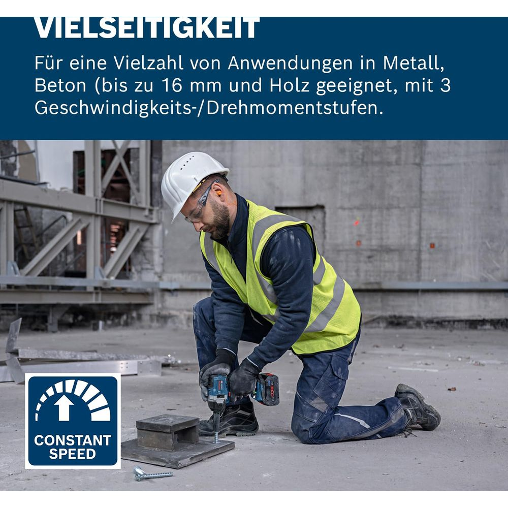Mann mit Helm und Warnweste bohrt in Beton.