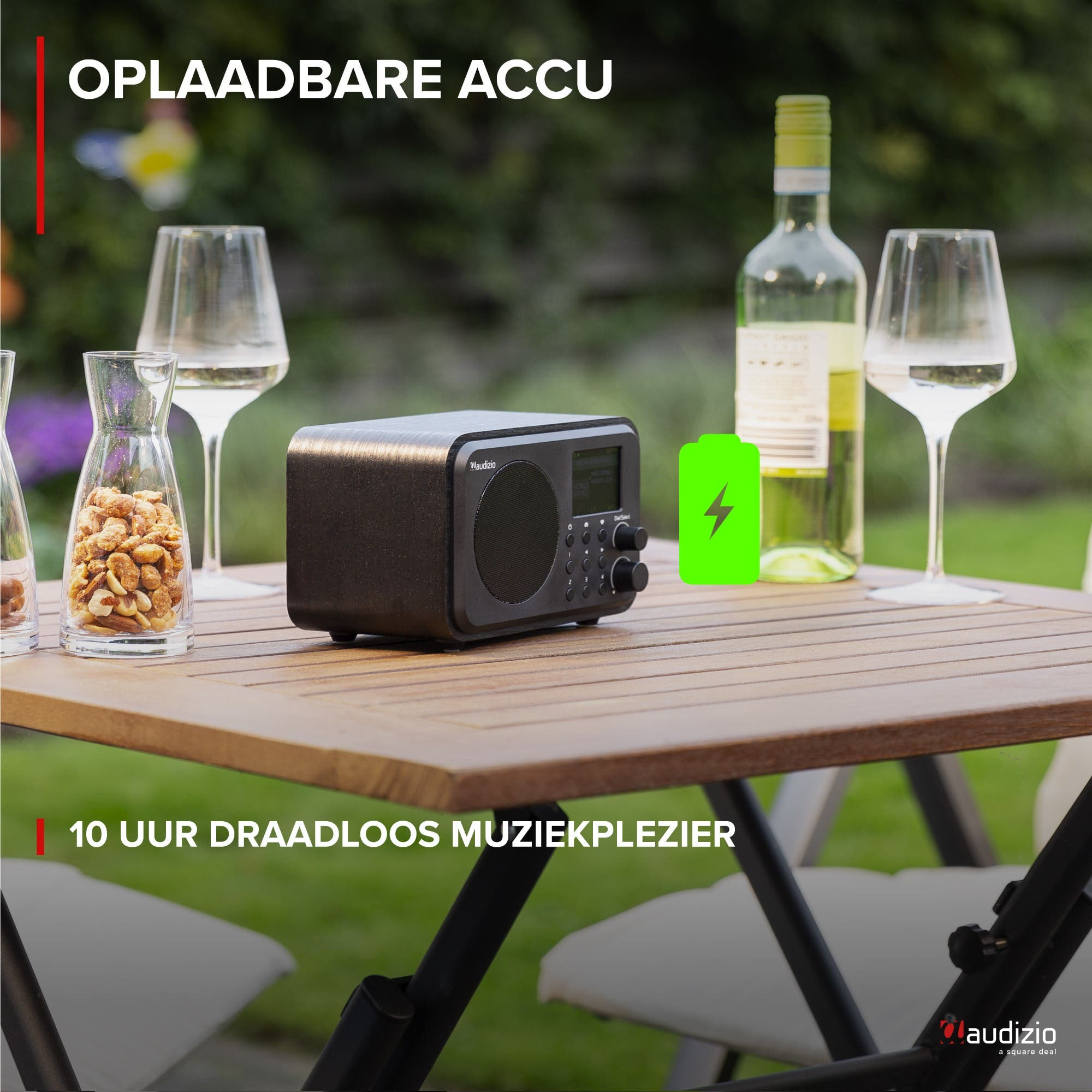 Una radio, vino, vasos y frutos secos sobre una mesa exterior.