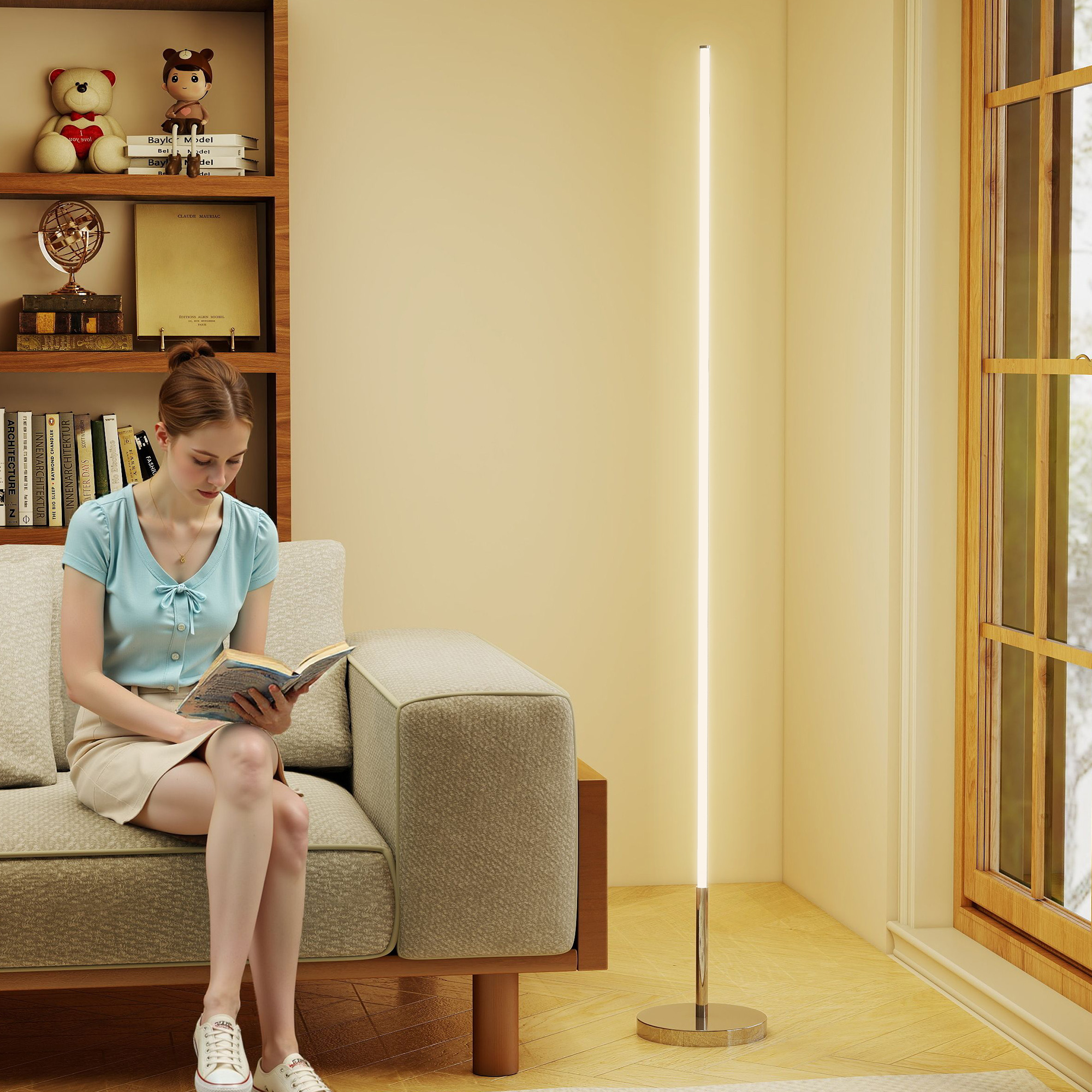 Una donna legge un libro su un divano, accanto a una lampada da terra e una libreria.